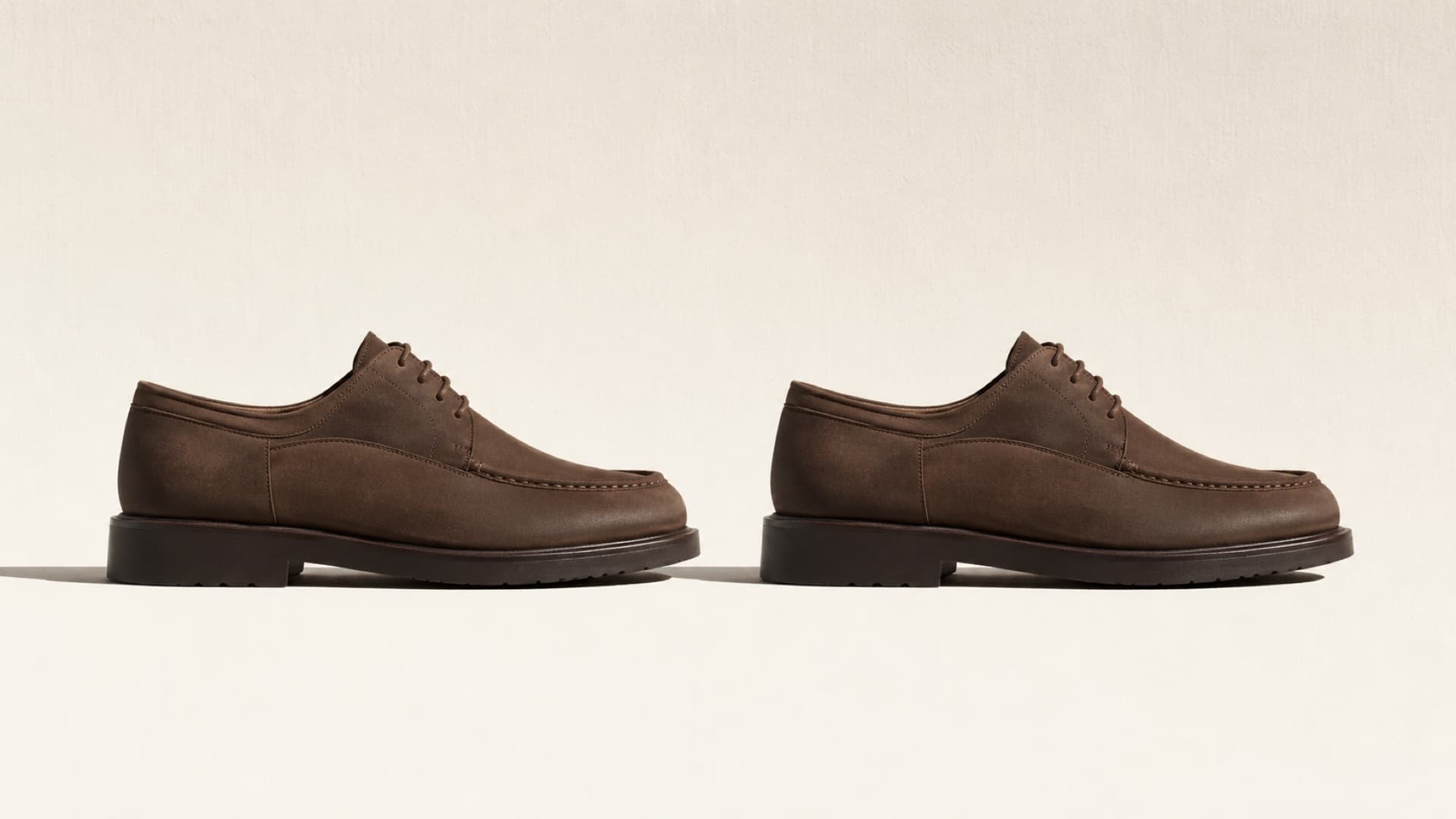Two identical-looking leather shoes standing side by side in exact side elevation, evenly lit.